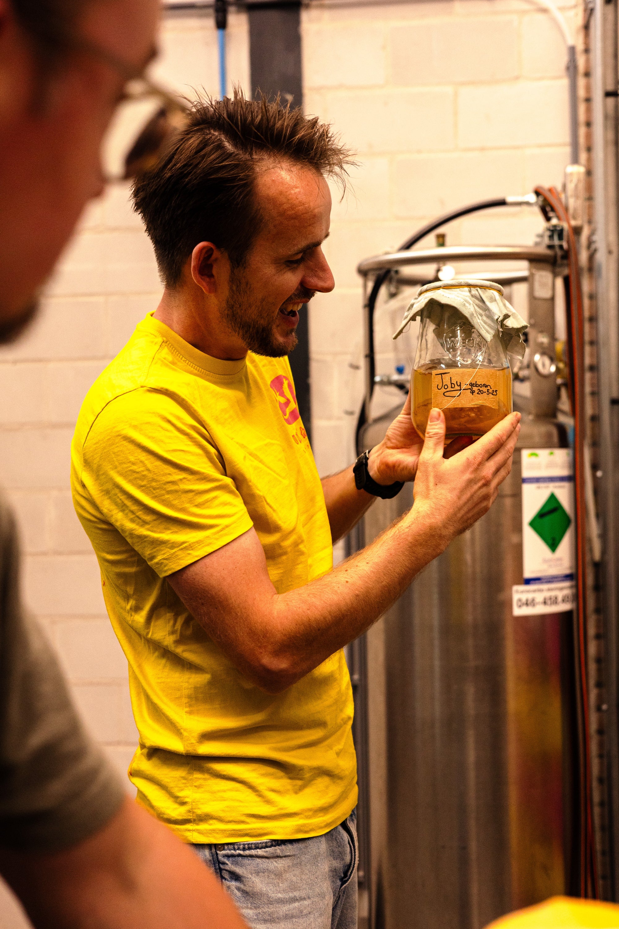 Joris van den Broek die uitlegt over fermentatie met een glazen pot kombucha SCOBY in zijn hand