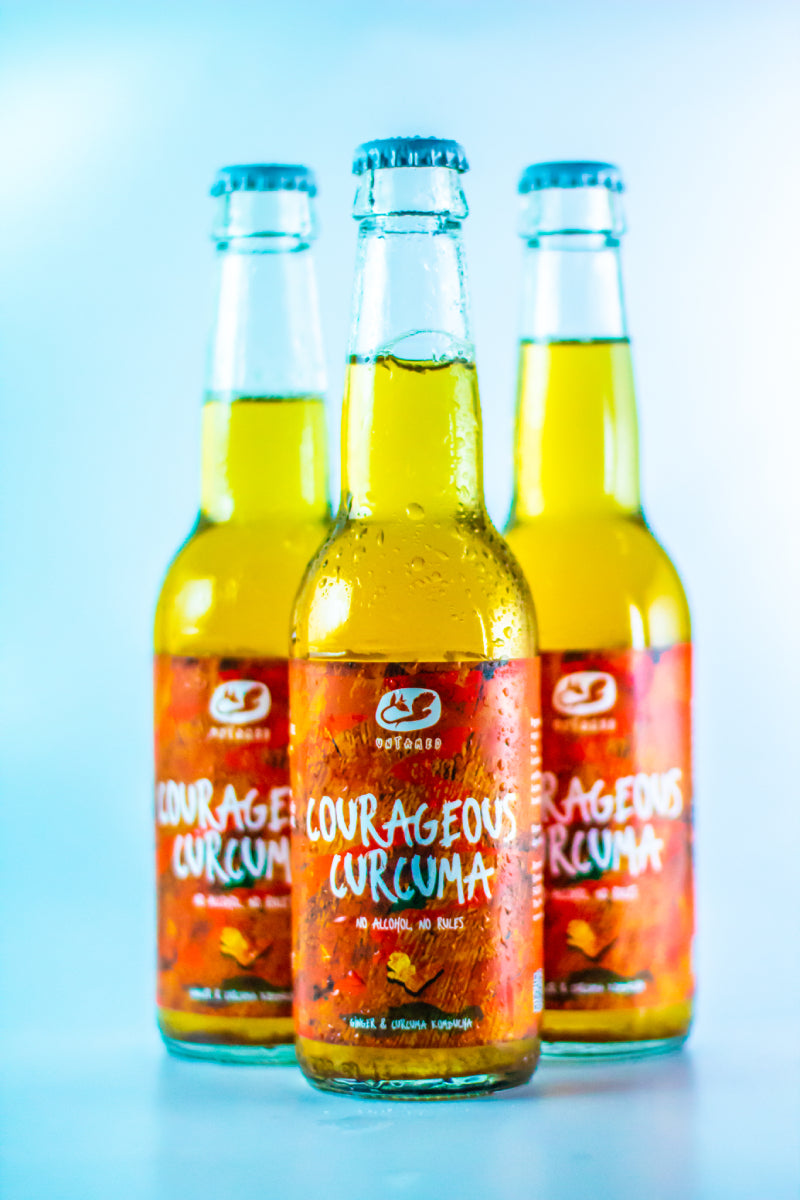 drie flesjes courageous curcuma kombucha met een lege achtergrond