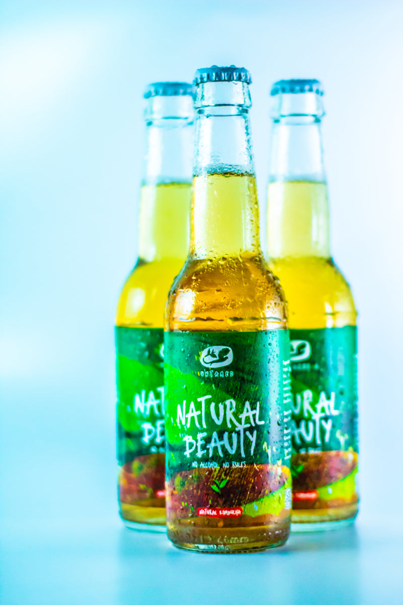Drie flesjes Natural Beauty van Untamed Kombucha met een lege achtergrond