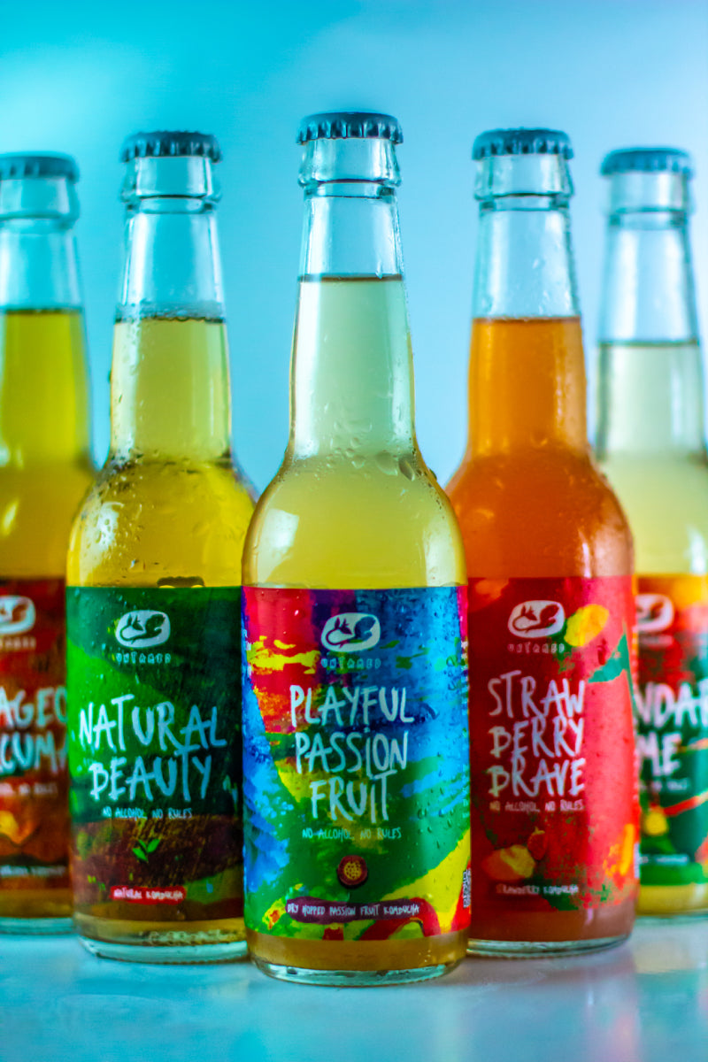 De vijf smaken van Untamed Kombucha, met een flesje Playful Passion Fruit voorop