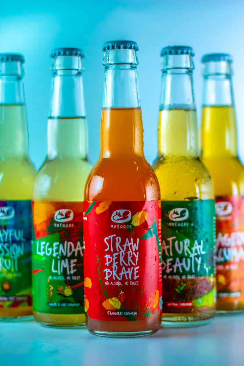 Alle vijf de smaken Untamed Kombucha in flesjes, met de Strawberry Brave als voorste flesje