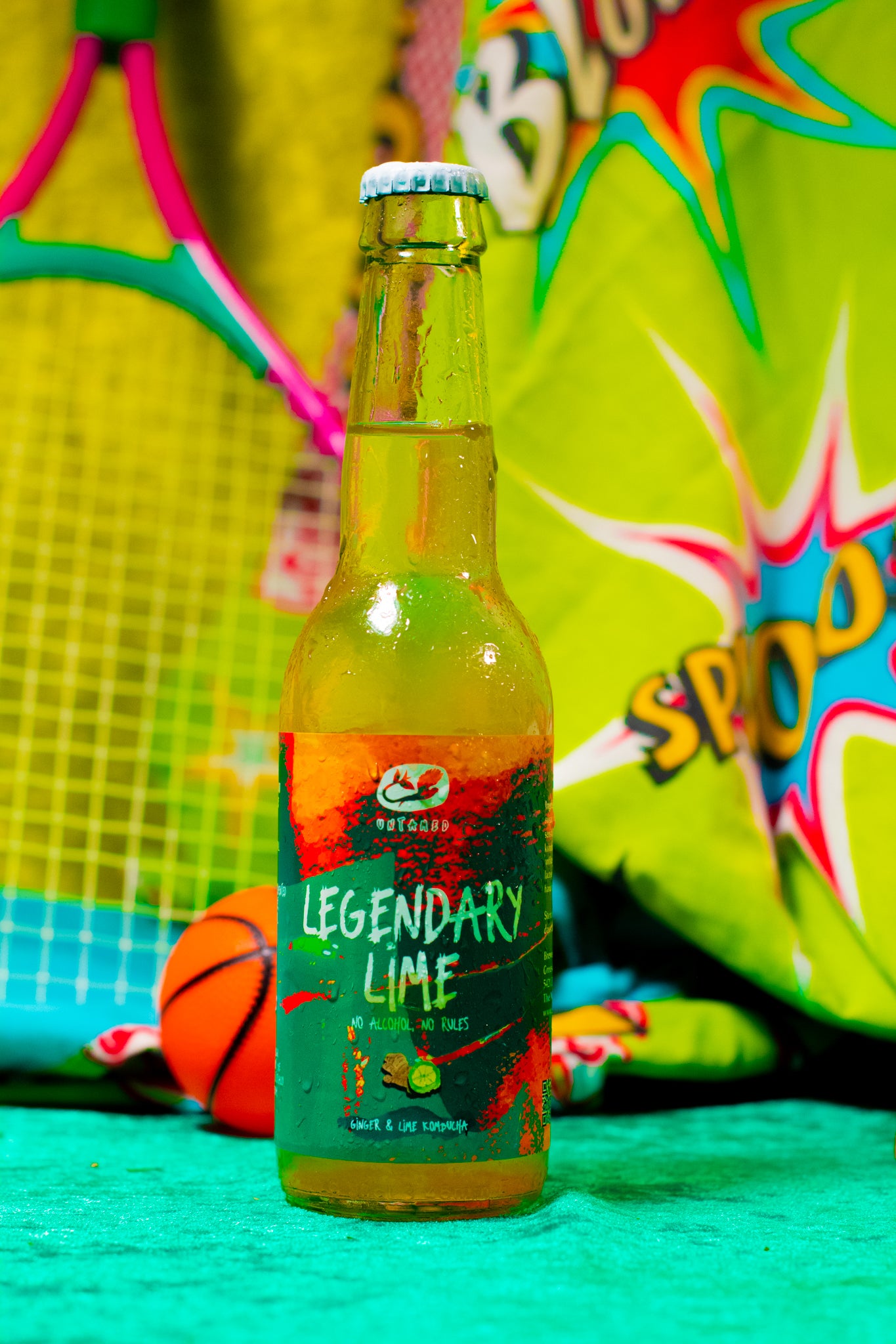 Legendary Lime Kombucha met een sportieve achtergrond waar je een tennisracket en een bal ziet.