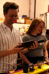 2 workshopdeelnemers houden een fles met beugel vast om de tweede fermentatie van kombucha in te doen 
